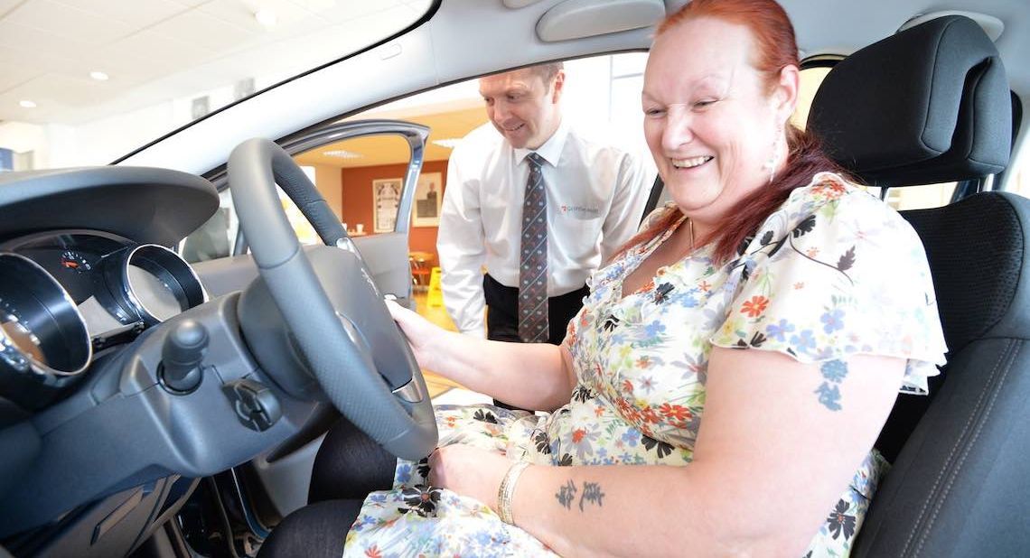 Happy woman trying out a new car at a showroom