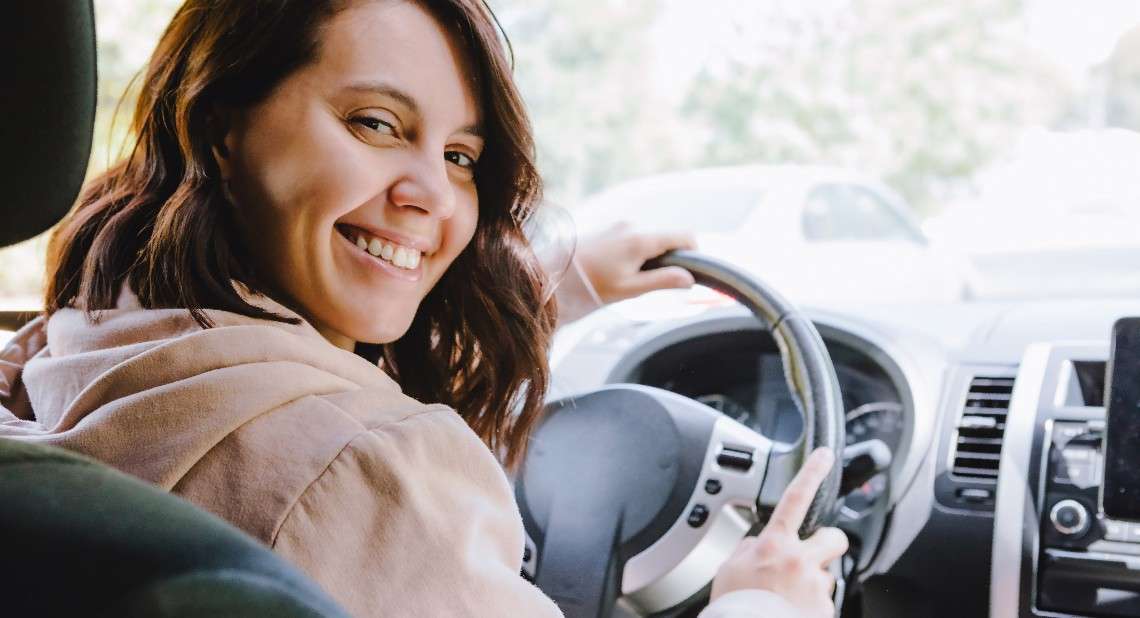 happy driver woman sitting in car confident in grasp of car insurance terminology
