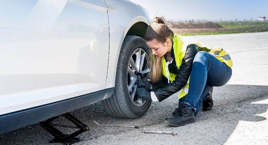 Woman changing damaged wheel and fixing it