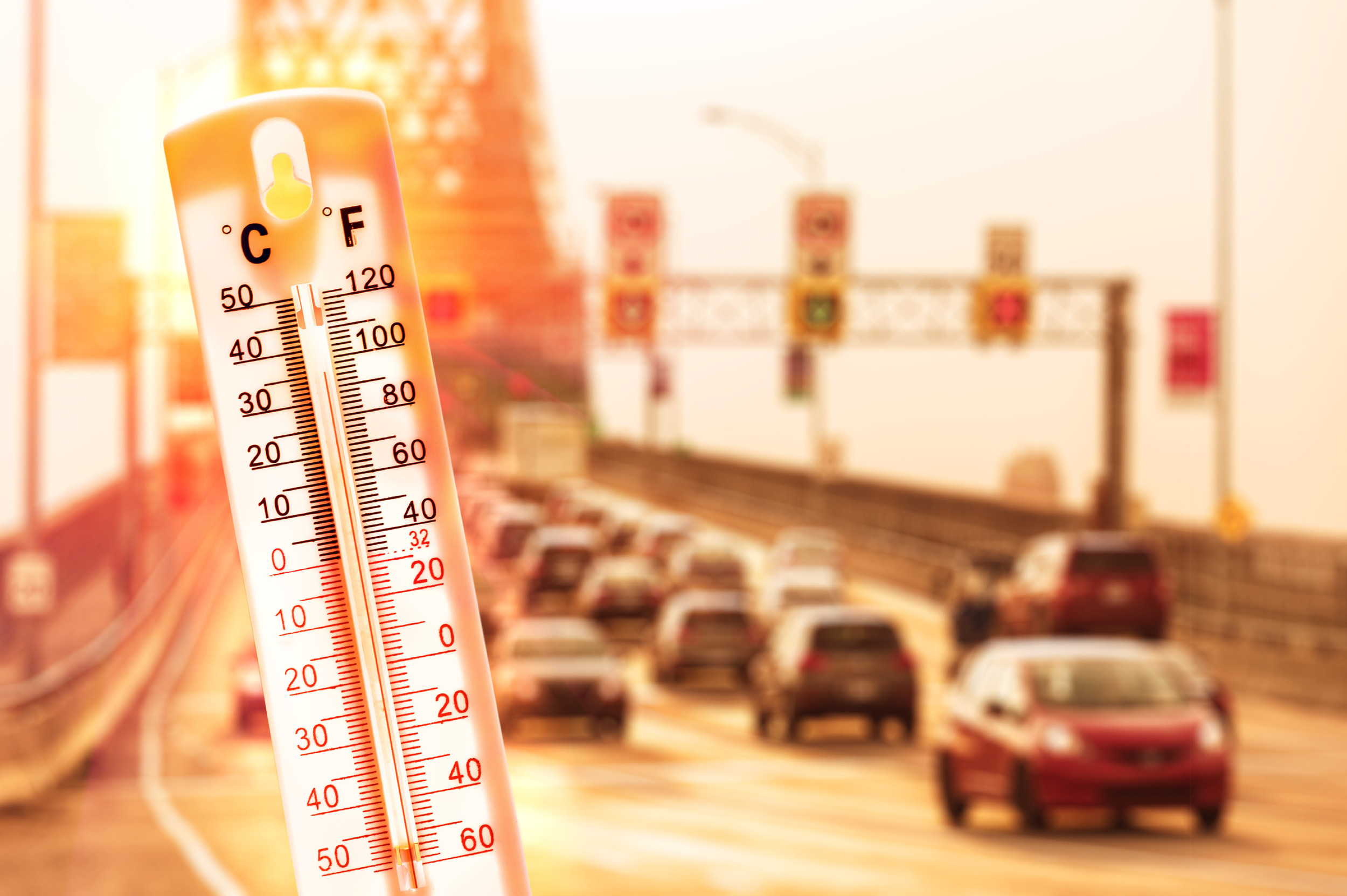 Thermometer in front of cars and traffic during heatwave in Montreal.