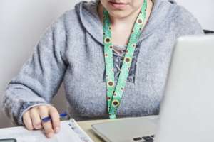 Woman studies or works while wearing a sunflower lanyard, representing invisible disabilities