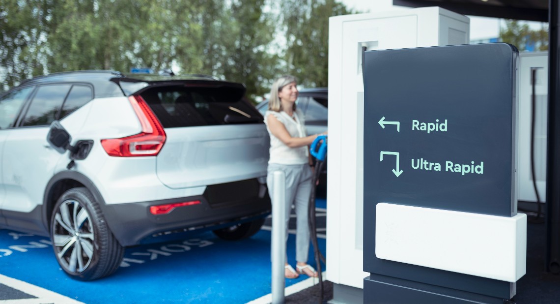 UK, York, Woman charging electric car at charging station