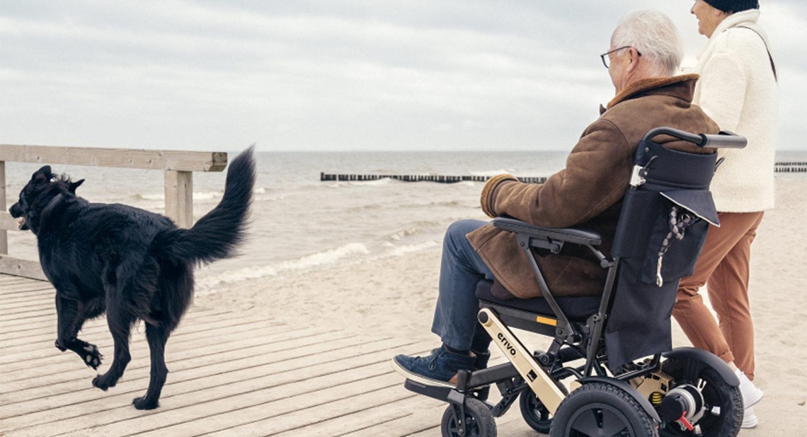 Man in a powered wheelchair on the peer with his dog