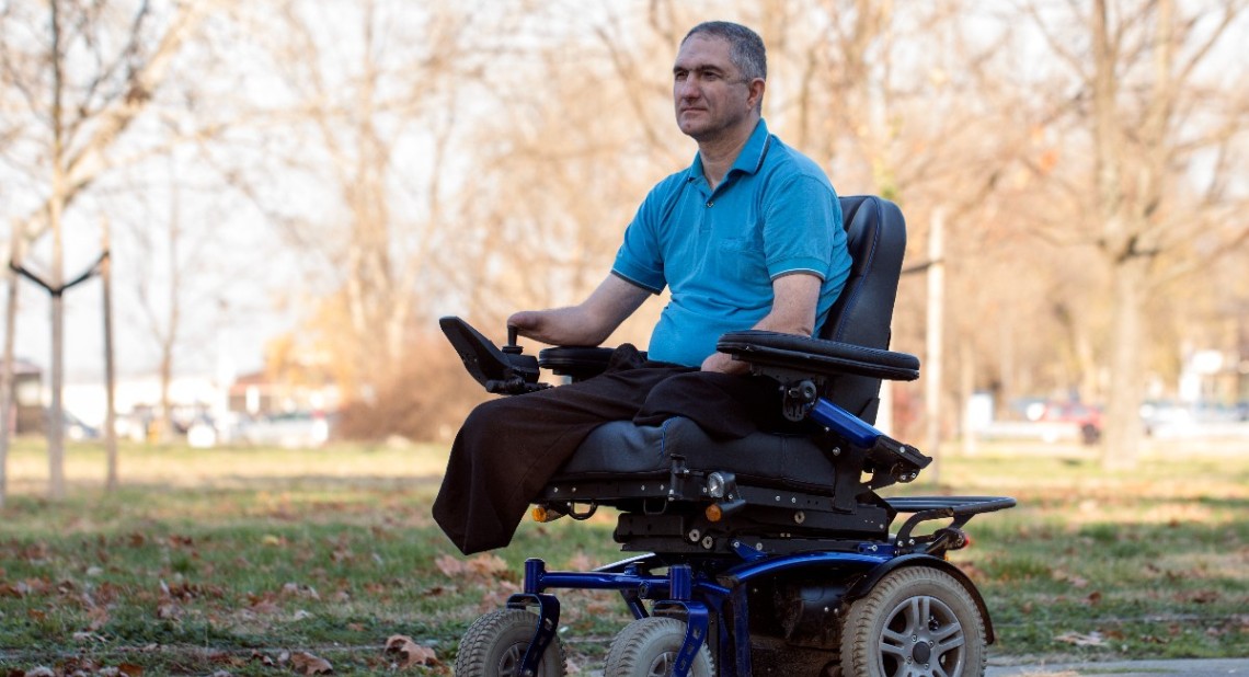 Man in electric wheelchair posing in a public park