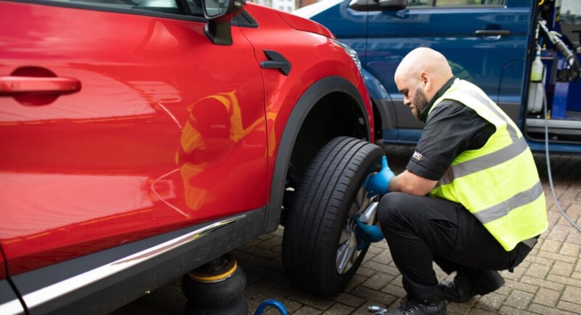 A Kwik Fit engineer installing new tyres on a red car