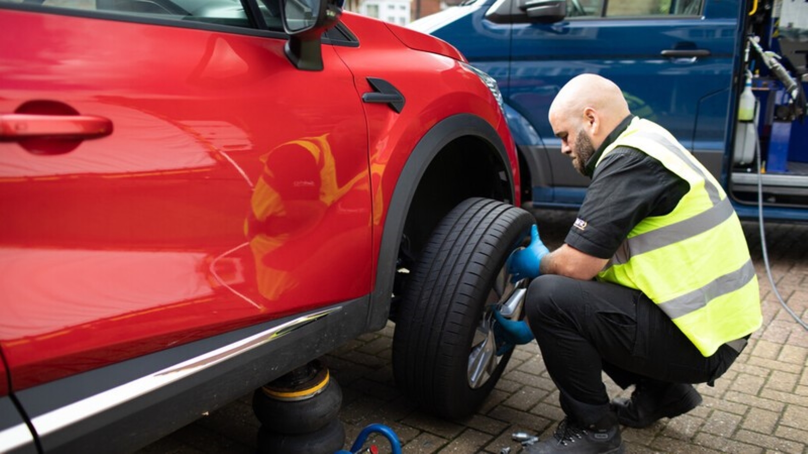 A Kwik Fit engineer installing new tyres on a red car