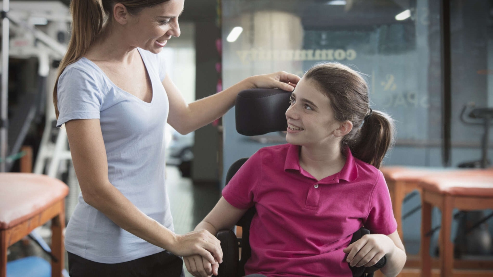 A female physical therapist comforting a little girl in a wheelchair.