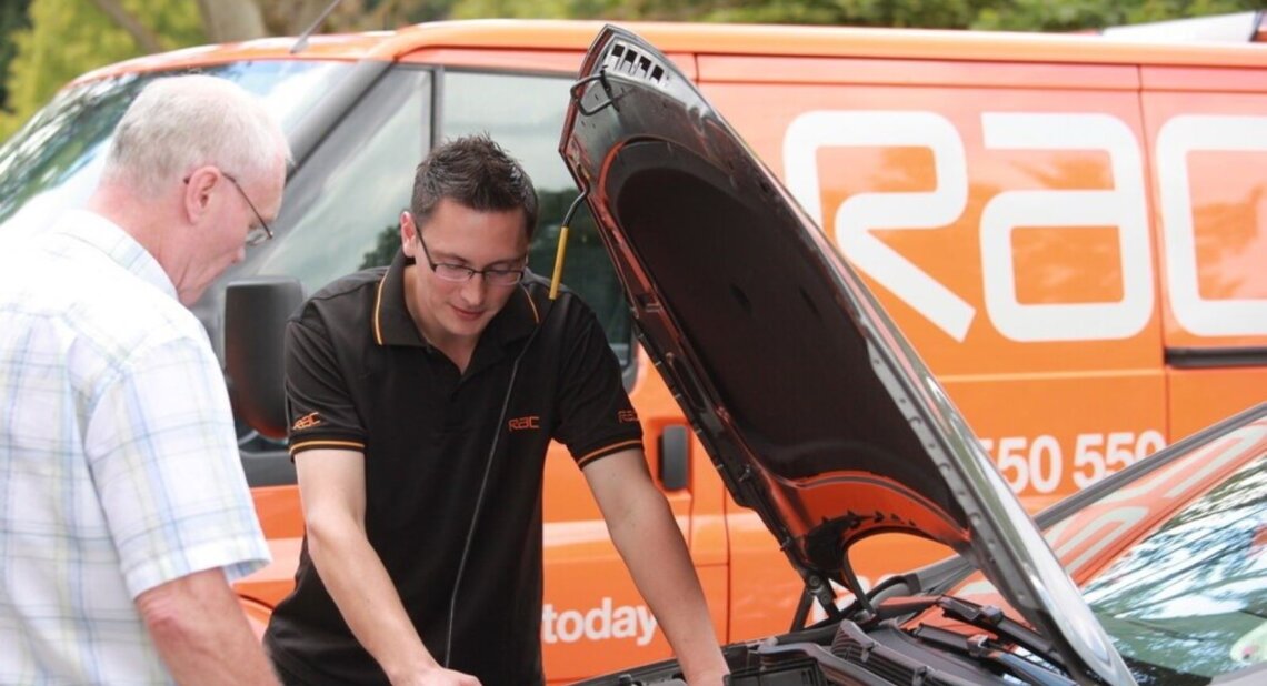 A RAC roadside engineer working on a car with the hood open