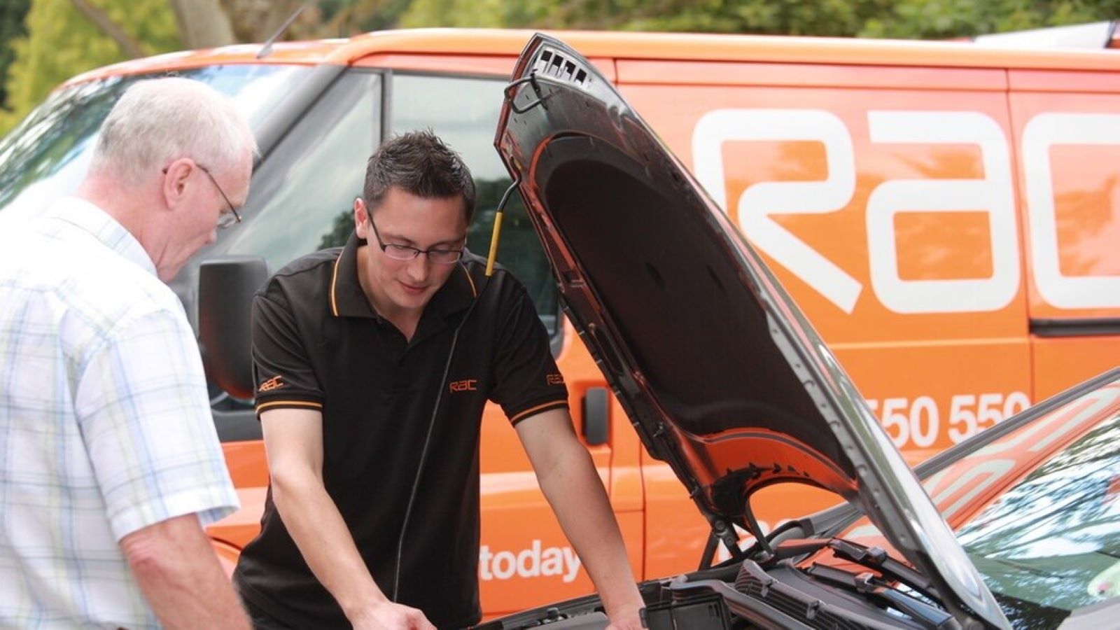A RAC roadside engineer working on a car with the hood open
