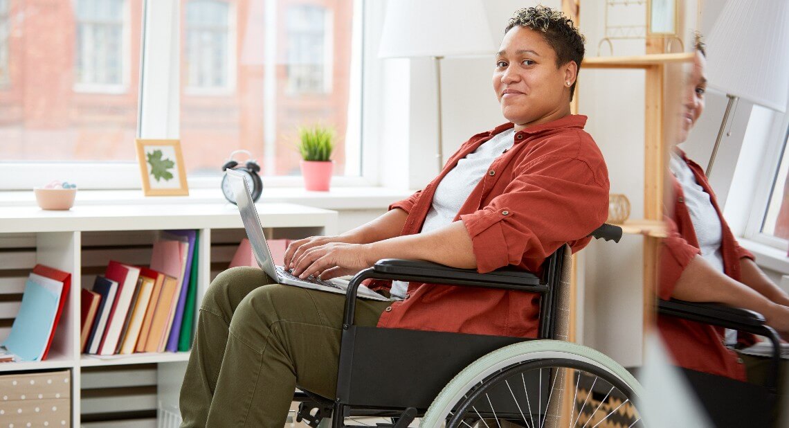 Woman in a wheelchair working on her laptop indoors