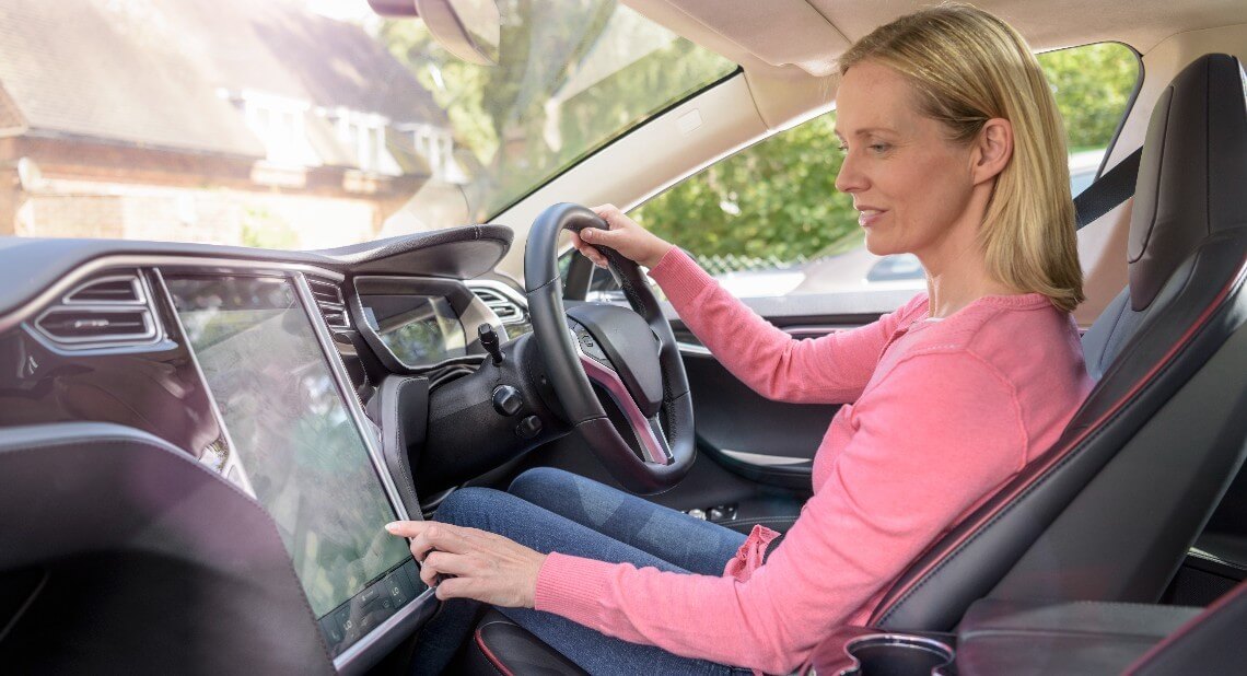 Woman driving an EV checking its safety features