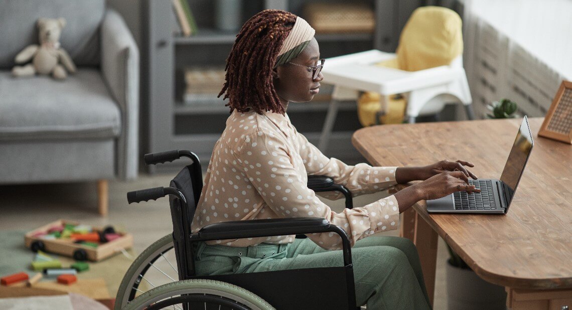 Woman in wheelchair on her laptop at home