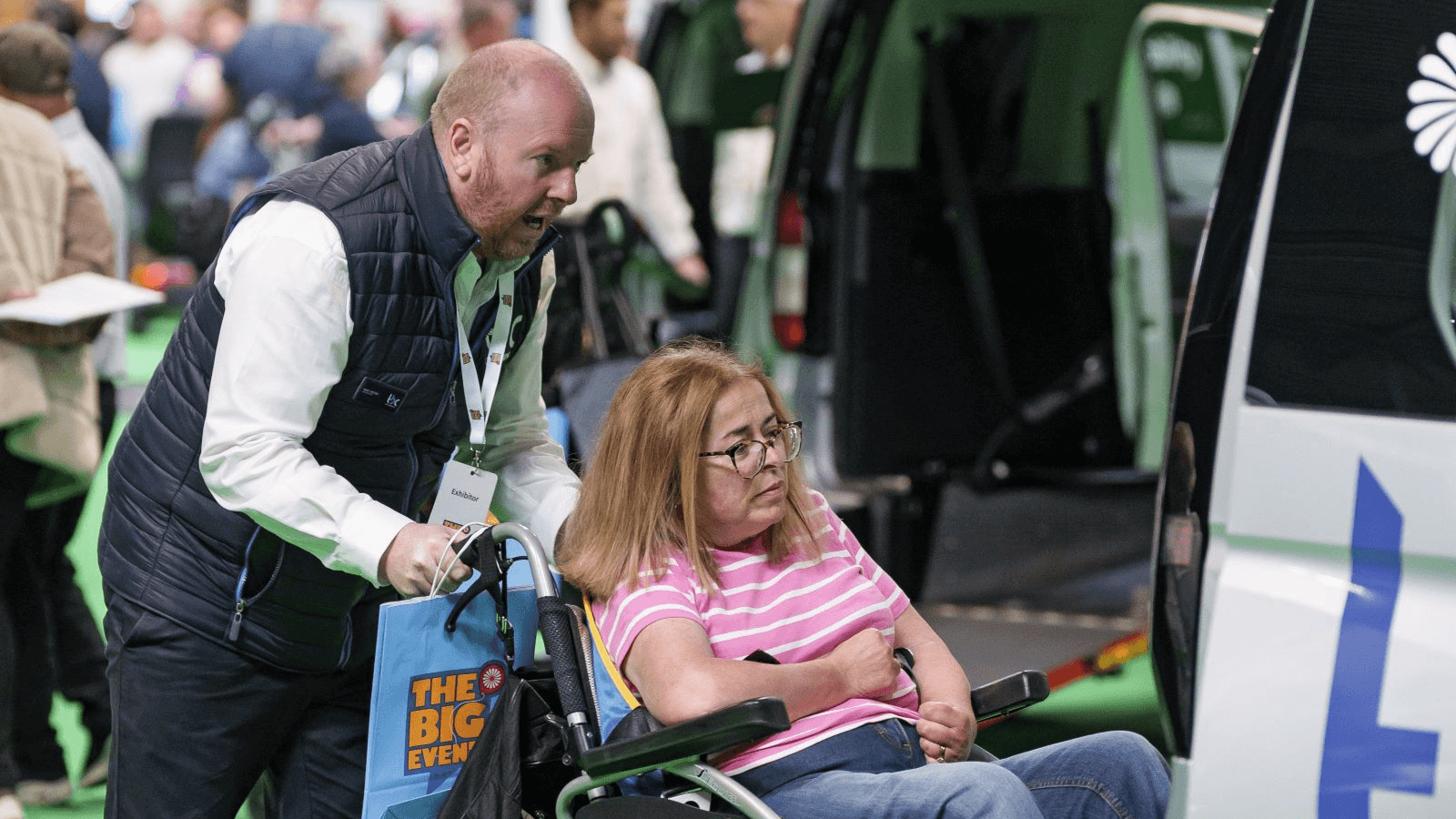 Woman in a wheelchair being pushed up a ramp into a Wheelchair Accessible Vehicle (WAV)