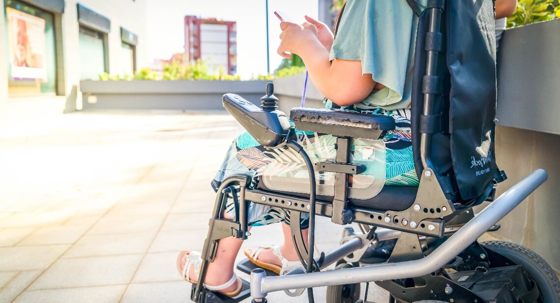 Woman in a powered wheelchair using her phone outside