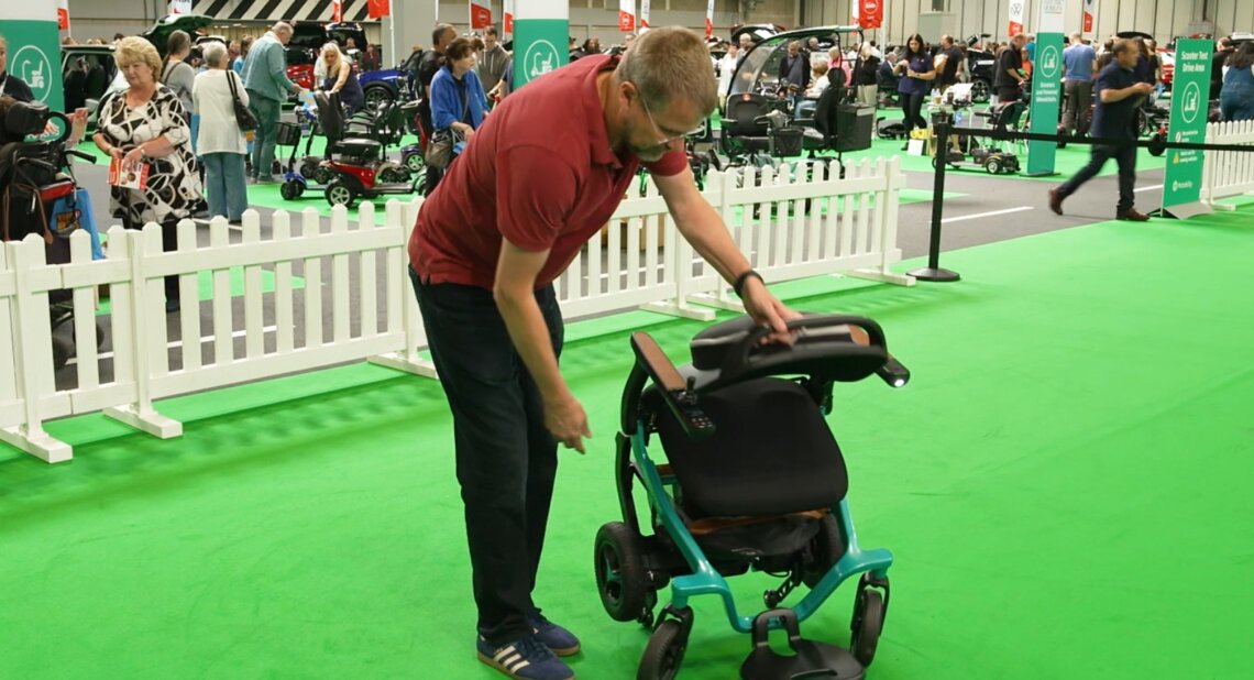 Jim Wood showing a demonstration of a powered wheelchair folding down