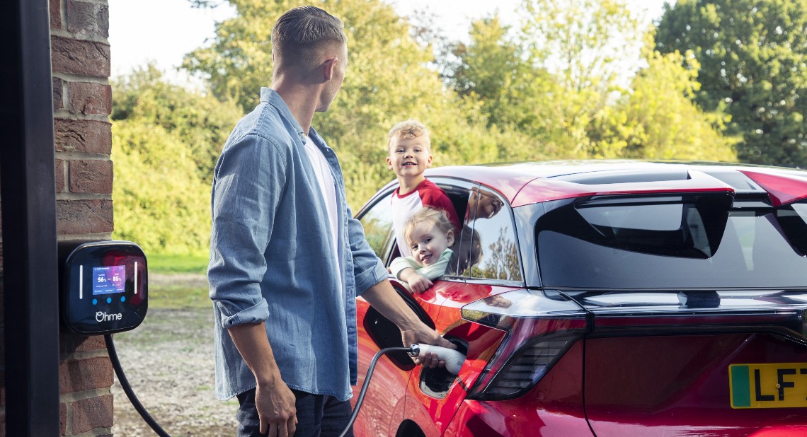 Man charging his EV at home with his kids in the car