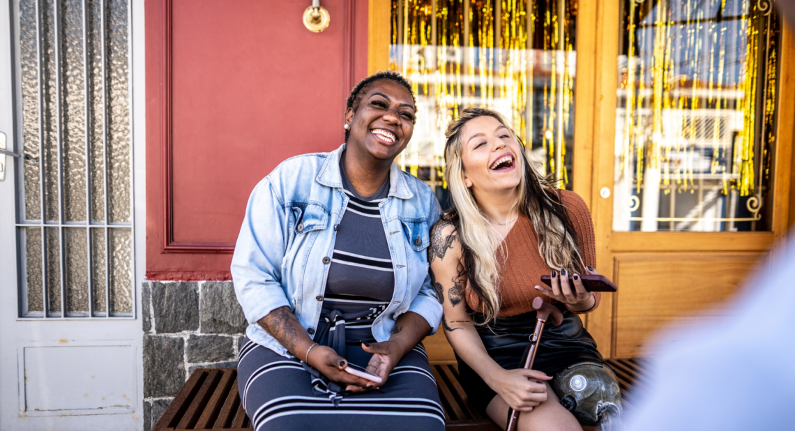 Two women sitting down laughing together