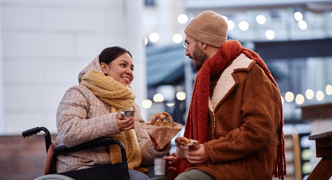 Man and woman sitting having a drink and snack outside in winter