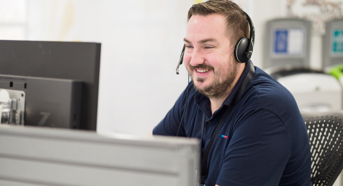 A smiling man in a headset in a customer service centre