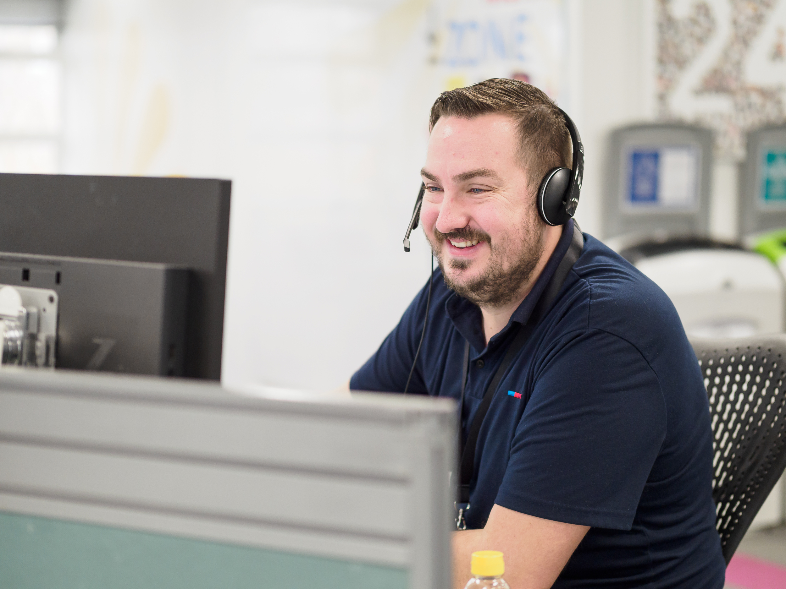 A smiling man in a headset in a customer service centre