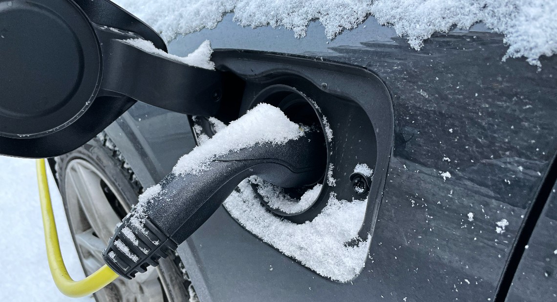 A close-up picture of an Electric Car being charged covered in snow.