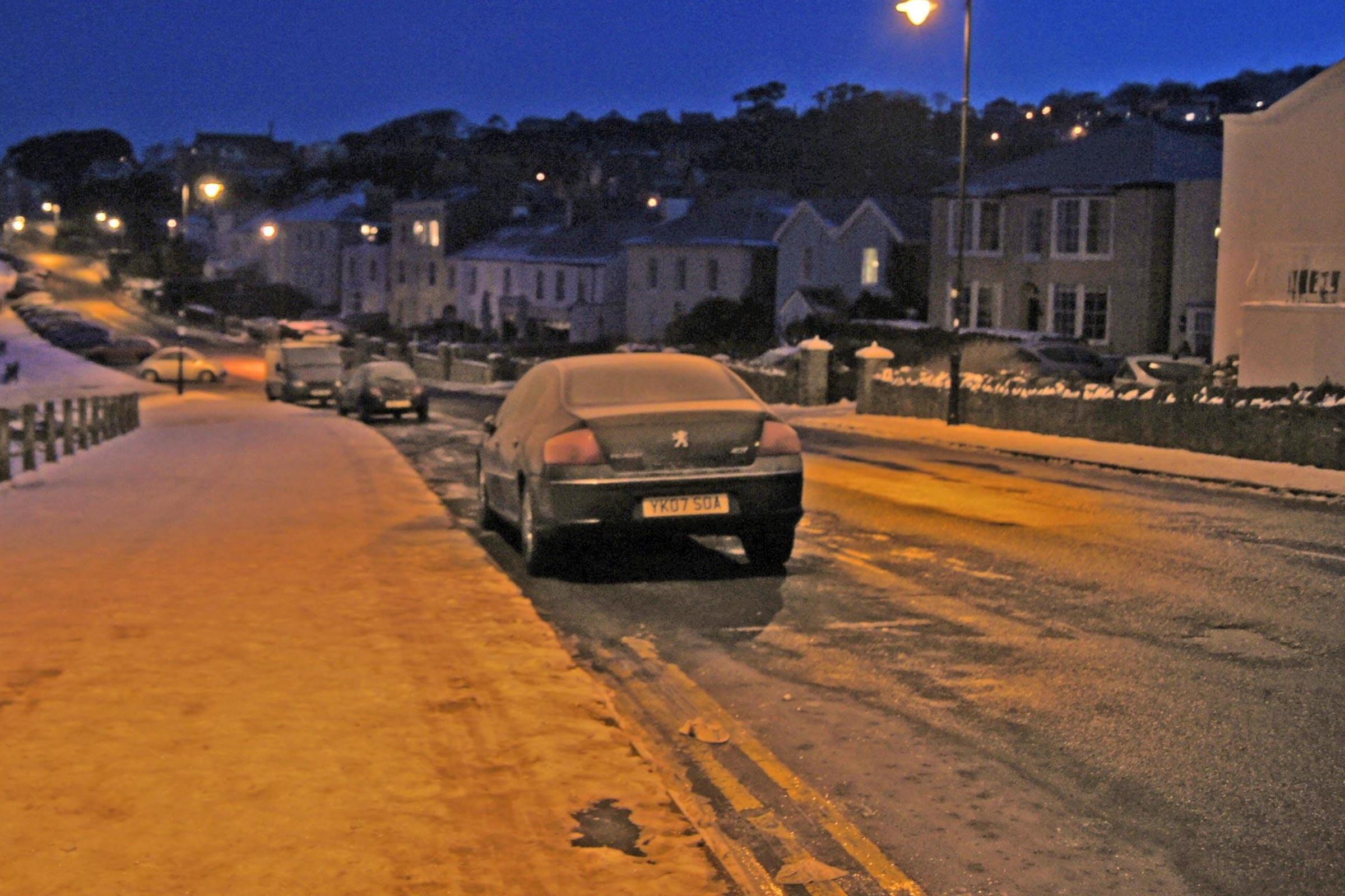 A snowy street with cars parked