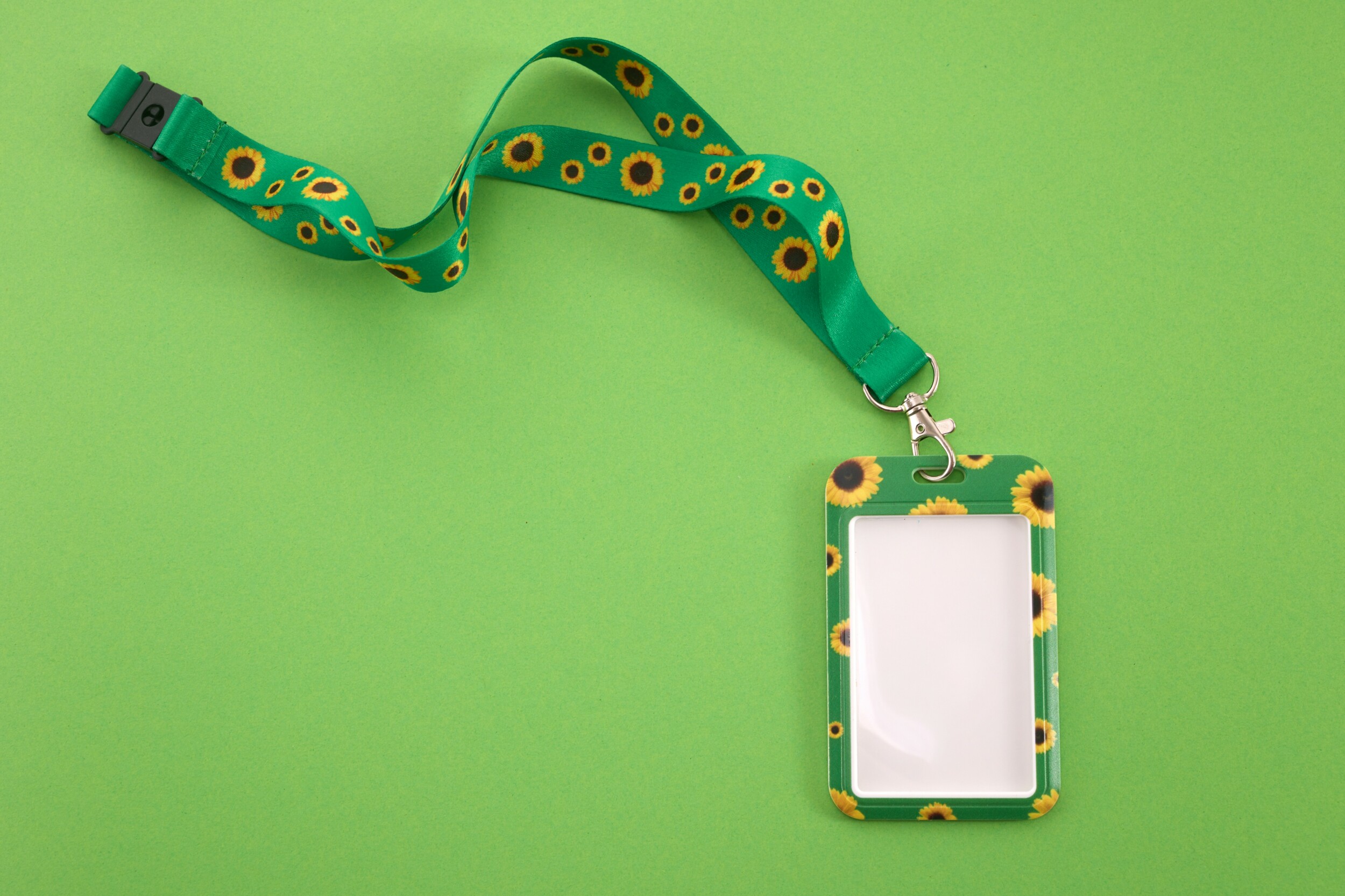 A vibrant green lanyard with sunflower motifs and an empty badge on a green background.