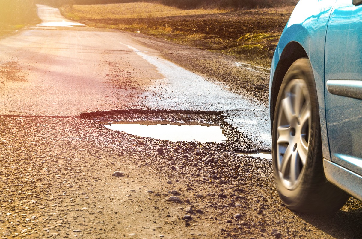 a pothole on a road featuring a car wheel