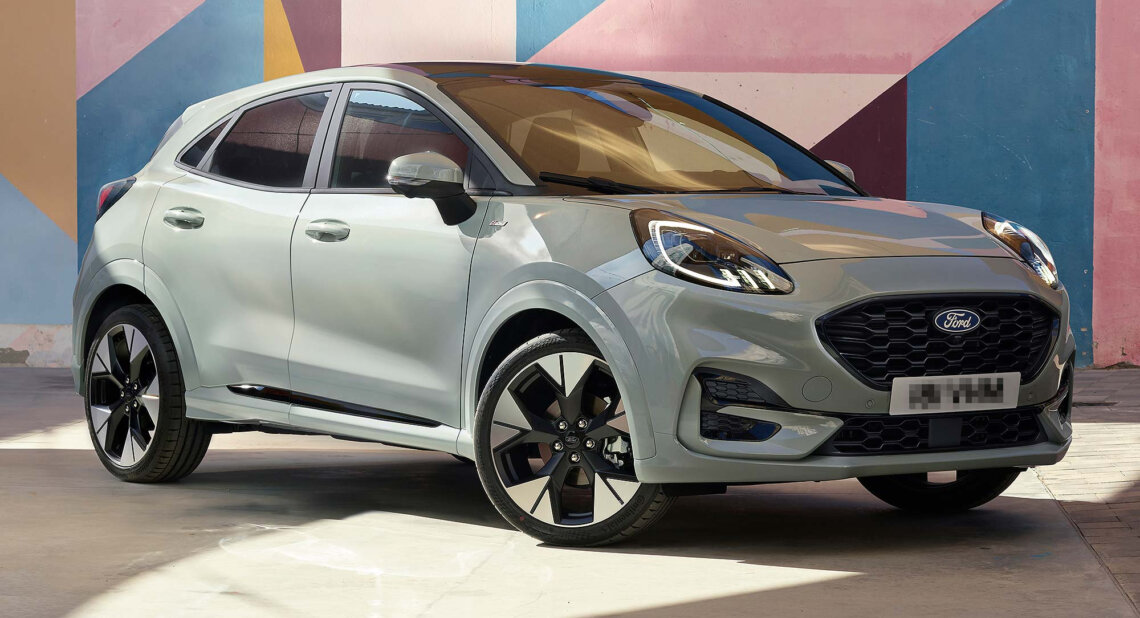A grey Ford Puma SUV parked in front of a colourful geometric mural, highlighting its sporty design and black alloy wheels.