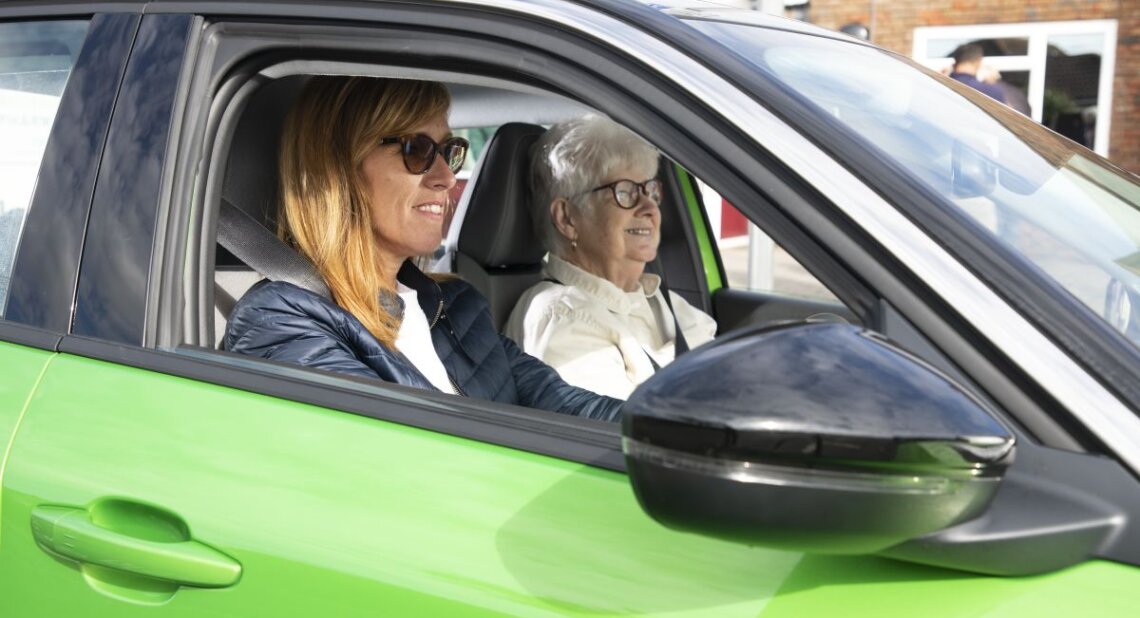 Two women in a green car smiling