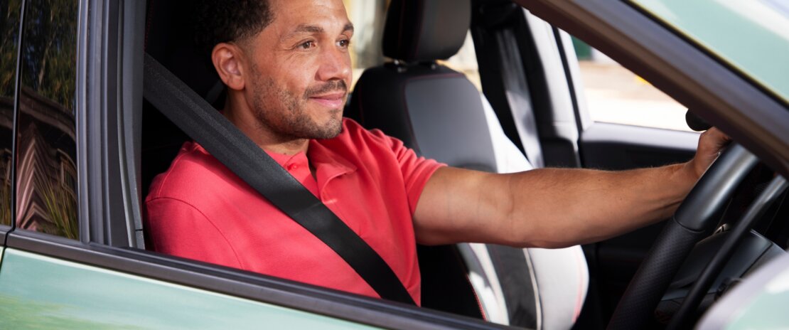 Man driving a car, wearing a seatbelt and looking ahead confidently. Drive Smart helps customers stay safe and build confidence on the road.