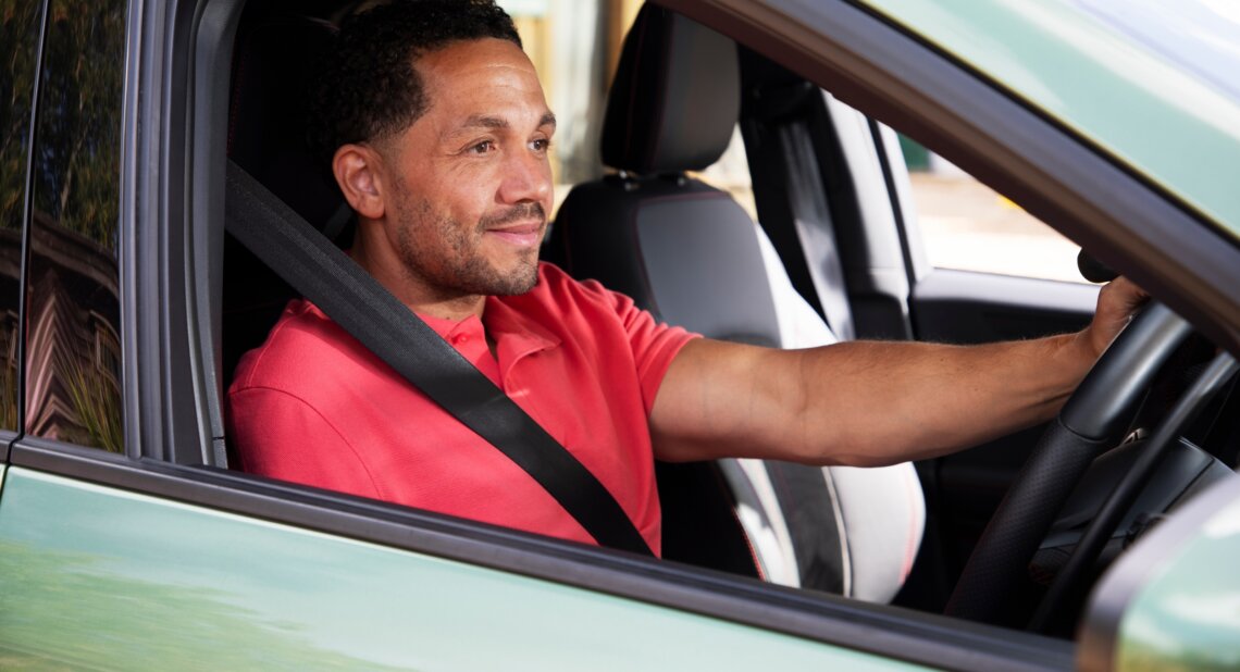 Man driving a car, wearing a seatbelt and looking ahead confidently. Drive Smart helps customers stay safe and build confidence on the road.