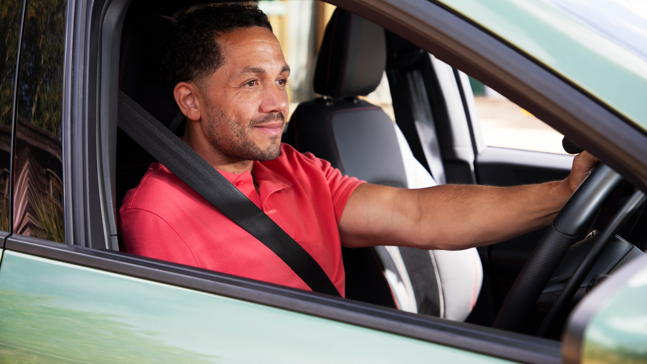 Man driving a car, wearing a seatbelt and looking ahead confidently. Drive Smart helps customers stay safe and build confidence on the road.