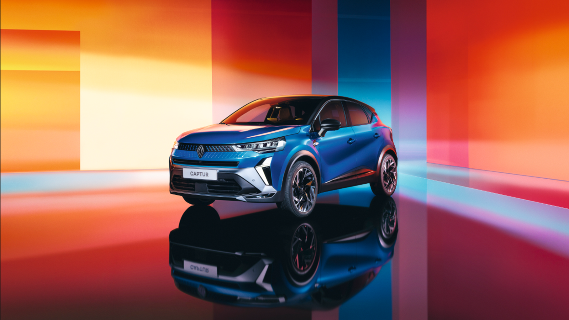 Blue Renault Captur displayed in a studio with colourful gradient lighting and reflective floor.